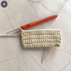 the crochet hook is next to an orange handled knitting needle