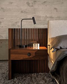 a nightstand with a lamp on top of it next to a bed