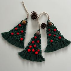 two christmas trees made from yarn with bells and balls on them, one is green and the other is red