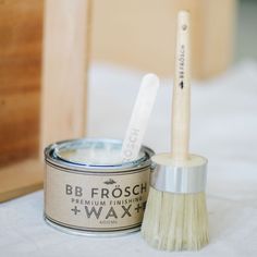 two toothbrushes in a tin next to a wooden box on a white tablecloth