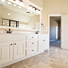 a large bathroom with white cabinets and marble flooring is seen in this image from the doorway