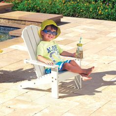 a little boy sitting in a white chair with a bottle of soda on his lap