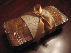 a piece of bread wrapped in plastic on top of a wooden table next to a brown ribbon