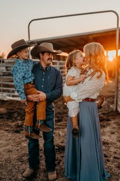 a family standing in front of a fence at sunset