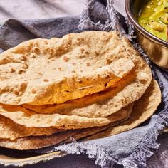 three pita breads sitting on top of a table next to a bowl of soup