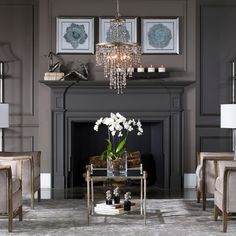 a living room filled with furniture and a chandelier hanging from the ceiling over a fire place