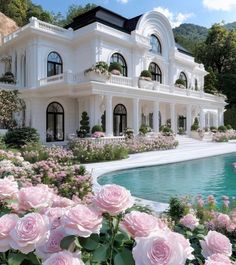 a large white house with lots of windows and pink flowers in front of the pool