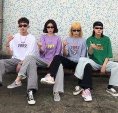 four people sitting on a bench with their hands in the air and one person wearing sunglasses