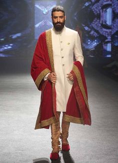 a man in a white and red outfit walks down the runway