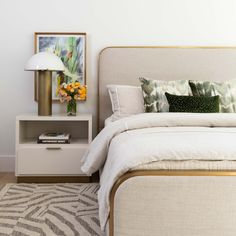 a bedroom with a bed, nightstands and pictures on the wall above it is shown