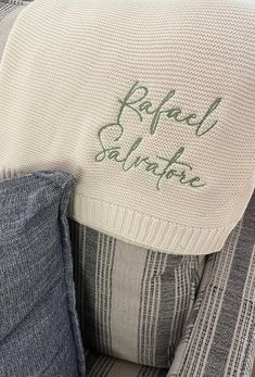 an upholstered chair with a pillow on it and the words rachel salita written in green