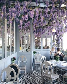 an indoor dining area with purple flowers hanging from the ceiling