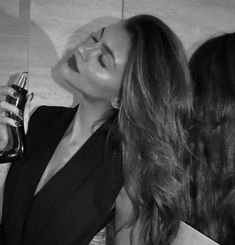 a woman in a black dress is holding a bottle