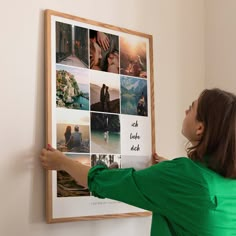 a woman placing pictures on a wall with her hands in the frame and pointing at them