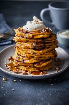 a stack of pancakes topped with whipped cream and pecans