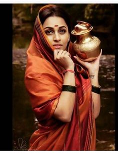 a woman in an orange sari holding a gold pot