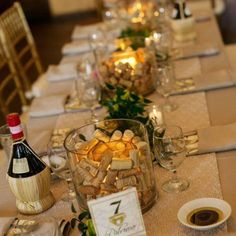 a long table is set with wine bottles and place settings for the guests to enjoy