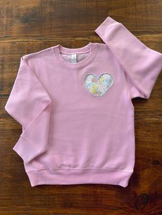 a pink sweatshirt with a heart on the front and sequins on the back