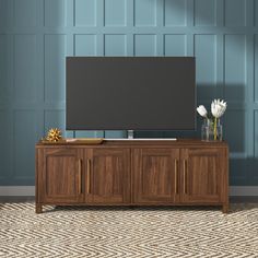 a large flat screen tv sitting on top of a wooden entertainment center cabinet in a living room