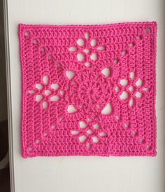 a pink crocheted square with hearts on it