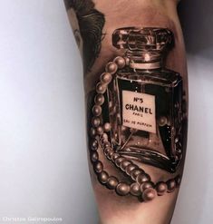 a man's leg with a chanel perfume bottle tattoo on it and beads