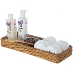 a wicker basket with two white towels and three hand soaps in it on a white background