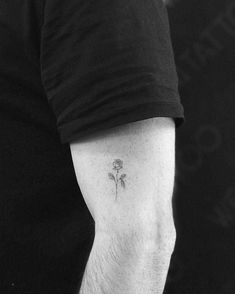 a man with a small flower tattoo on his arm