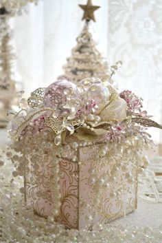 a small box with pearls and flowers on it sitting on a table next to other decorations