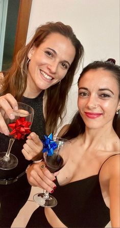 two women holding wine glasses with bows on them