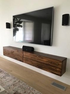 a flat screen tv mounted to the side of a wooden entertainment center in a living room