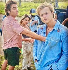 two young men standing next to each other in front of a group of people with backpacks