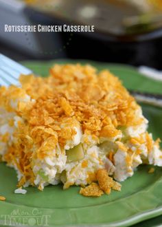 a green plate topped with a casserole covered in cheese and topping next to a fork