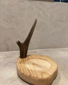 an antler's head in a wooden holder on a counter top next to a wall