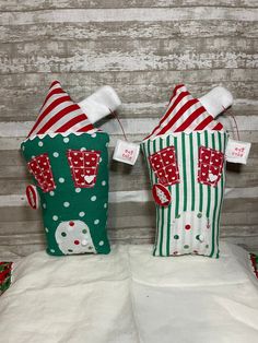 two green and red christmas bags sitting on top of a white bed next to each other