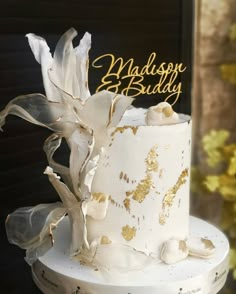 a white and gold wedding cake with flowers on top