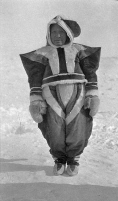 an old black and white photo of a person in a costume on the snow covered ground