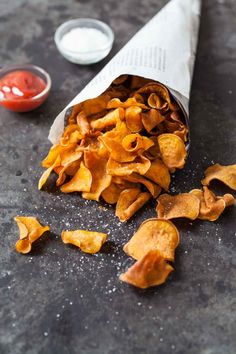 some food that is laying on the ground next to a paper bag with chips in it