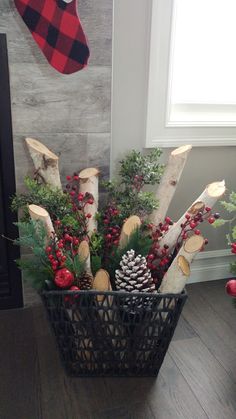 a basket filled with pine cones and evergreens on top of a wooden floor next to a fireplace