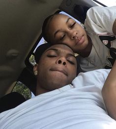 a man and woman laying in the back of a car