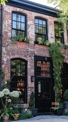 an old brick building with lots of windows and plants growing on the side of it