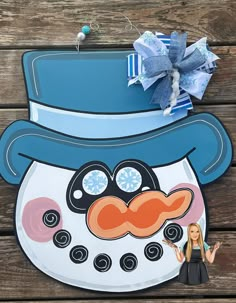 a paper cut out of a snowman with a blue hat and mustache on it