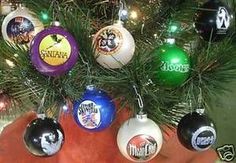 christmas ornaments are hanging from the tree in front of a man's hand, which is holding an ornament