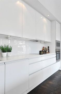 a kitchen with white cabinets and wooden floors