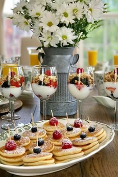 desserts and glasses on a table with flowers in the background