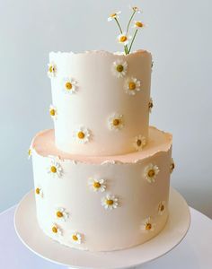 a three tiered cake with daisies on top