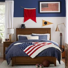 a bed with an american flag comforter on it in a blue and white bedroom