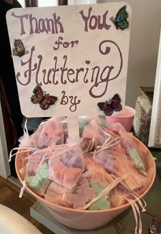 a bowl filled with pink and green candies next to a sign that says thank you for fluttering