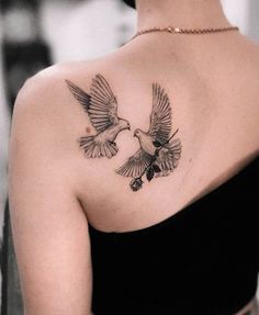 a woman with a tattoo on her shoulder and two birds flying above her back,