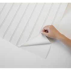 a hand is holding the edge of a piece of white paper with lines on it