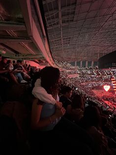 people are sitting in the bleachers at an arena with red lights on them